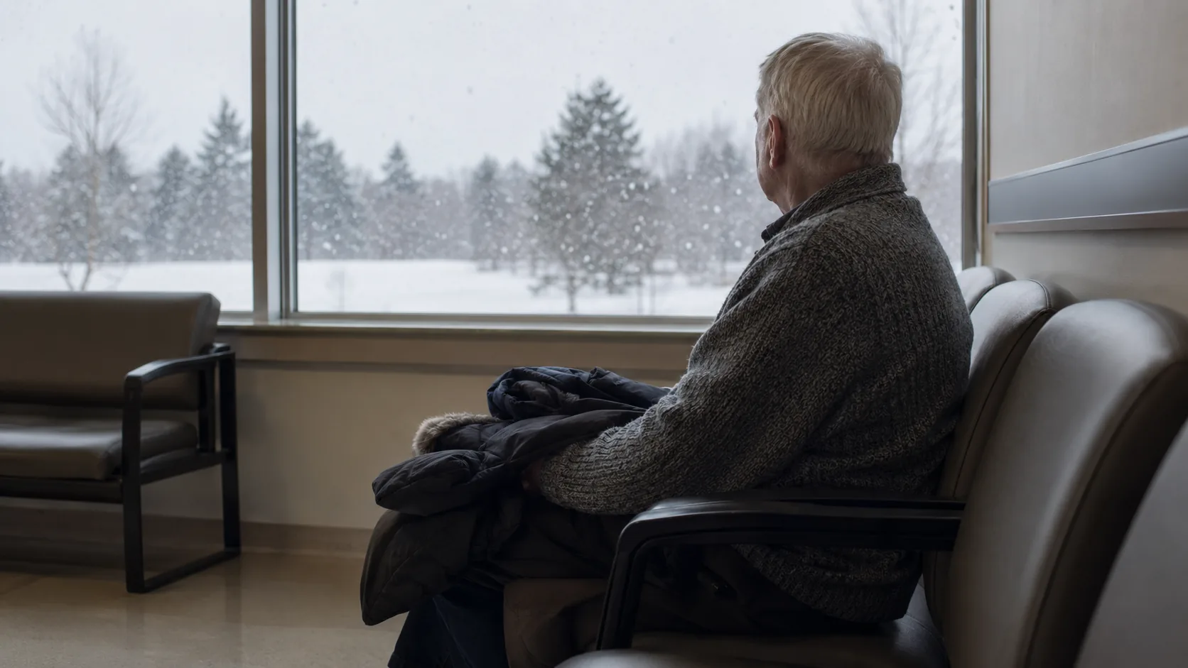 Man waiting alone by a hospital window in winter
